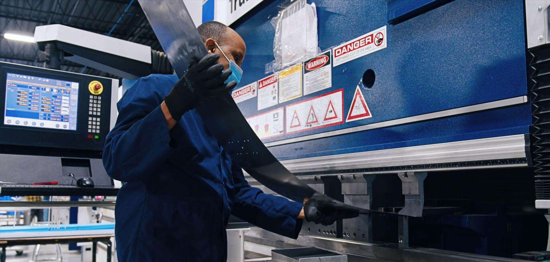 Man bending a sheet of metal using a CNC bending machine