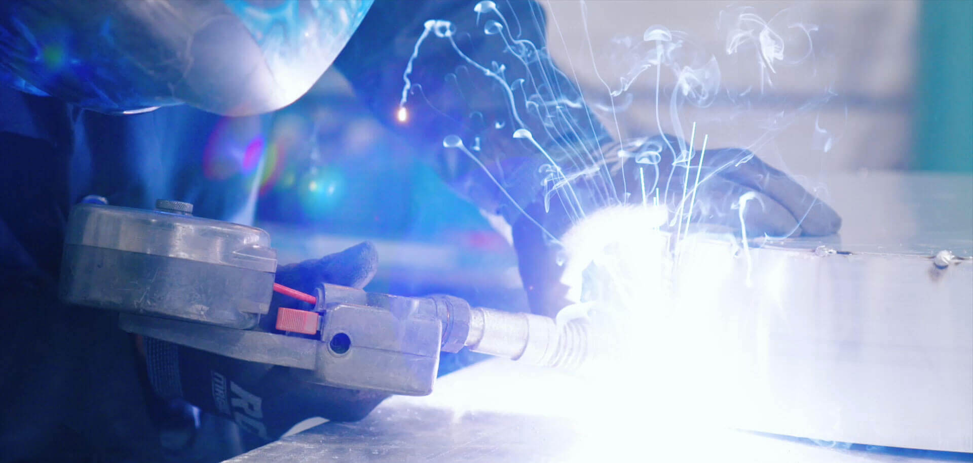 Welder welding metal pieces together with sparks flying